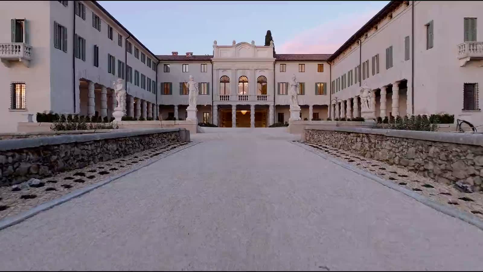 A candlelit table set in a hall of the villa at dusk